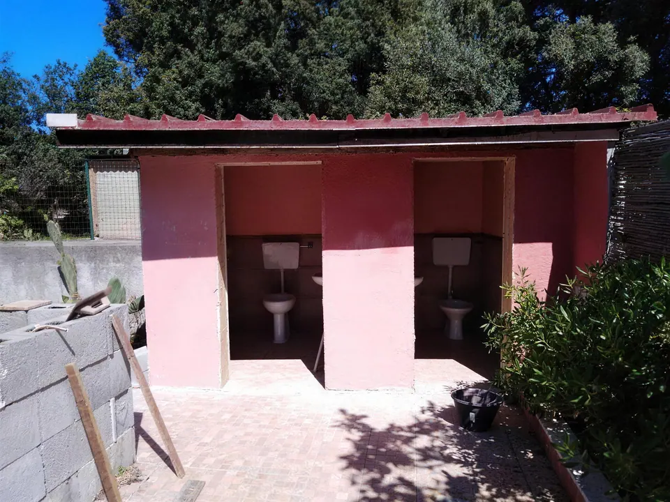 Blocco bagni esterno prima dei lavori, intonaco rosa ammalorato