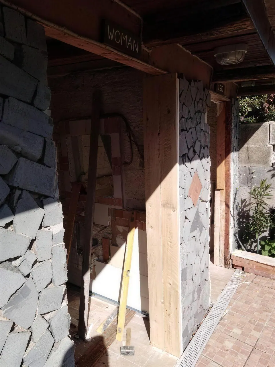 Ingresso di un bagno con muro in pietra lavica e nuovo telaio porta in legno